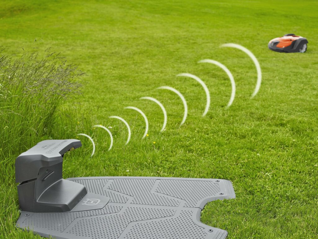 Ladestation kommuniziert mit einem Mähroboter, der im Garten arbeitet